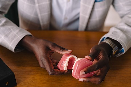 Dr. Femi holding a dental model while explaining treatment