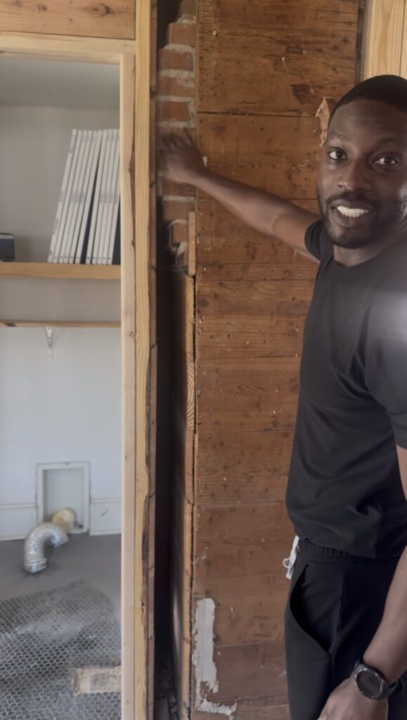 Dr. Femi Fadahunsi beside the original 1901 fireplace uncovered inside a wall during the renovation