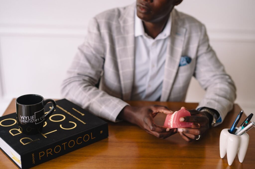 Dr. Femi Fadahunsi seated at his desk with a dental model at Wylie Dentistry Co.